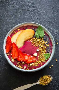 Acai smoothie kaseyle chia tohum, meyve, meyve (çilek) ve arı polen sağlıklı vegan vejetaryen diyet çiğ kahvaltı için. Güler yüzlü kase siyah arka plan üzerine kahvaltı, alanı Kopyala.