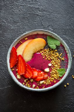 Acai smoothie kaseyle chia tohum, meyve, meyve (çilek) ve arı polen sağlıklı vegan vejetaryen diyet çiğ kahvaltı için. Siyah arka plan üzerine güler yüzlü kase kahvaltı.