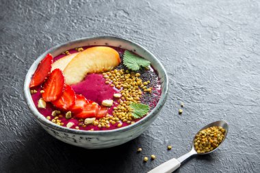 Acai smoothie kaseyle chia tohum, meyve, meyve (çilek) ve arı polen sağlıklı vegan vejetaryen diyet çiğ kahvaltı için. Güler yüzlü kase siyah arka plan üzerine kahvaltı, alanı Kopyala.