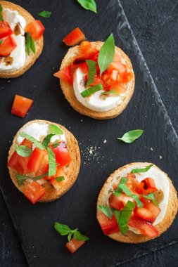 Doğranmış domates, fesleğen, mozzarella peyniri ve balsamik sirke ile İtalyan bruschetta. Taze ev yapımı caprese bruschetta veya crostini siyah taş zemin, kopya alanı üzerinde.
