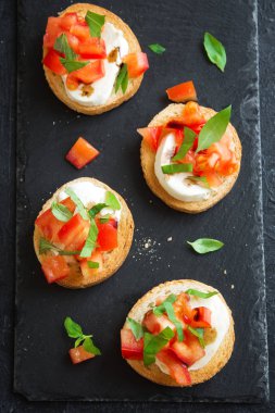 Doğranmış domates, fesleğen, mozzarella peyniri ve balsamik sirke ile İtalyan bruschetta. Taze ev yapımı caprese bruschetta veya crostini siyah taş zemin, kopya alanı üzerinde.