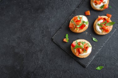 Doğranmış domates, fesleğen, mozzarella peyniri ve balsamik sirke ile İtalyan bruschetta. Taze ev yapımı caprese bruschetta veya crostini siyah taş zemin, kopya alanı üzerinde.