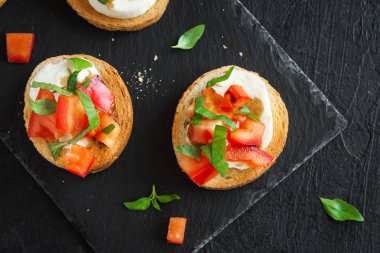 Doğranmış domates, fesleğen, mozzarella peyniri ve balsamik sirke ile İtalyan bruschetta. Taze ev yapımı caprese bruschetta veya crostini siyah taş zemin, kopya alanı üzerinde.