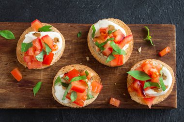 Doğranmış domates, fesleğen, mozzarella peyniri ve balsamik sirke ile İtalyan bruschetta. Taze ev yapımı caprese bruschetta veya crostini ve siyah arka plan üzerine malzemeler.