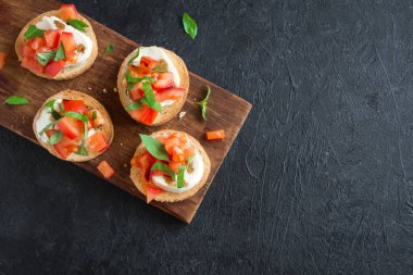 Doğranmış domates, fesleğen, mozzarella peyniri ve balsamik sirke ile İtalyan bruschetta. Taze ev yapımı caprese bruschetta veya crostini ve siyah arka plan üzerine malzemeler.