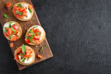 Doğranmış domates, fesleğen, mozzarella peyniri ve balsamik sirke ile İtalyan bruschetta. Taze ev yapımı caprese bruschetta veya crostini siyah taş zemin, kopya alanı üzerinde.