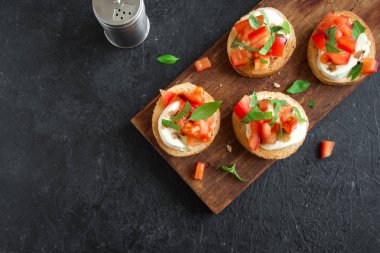 Doğranmış domates, fesleğen, mozzarella peyniri ve balsamik sirke ile İtalyan bruschetta. Taze ev yapımı caprese bruschetta veya crostini siyah taş zemin, kopya alanı üzerinde.