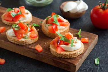 Doğranmış domates, fesleğen, mozzarella peyniri ve balsamik sirke ile İtalyan bruschetta. Taze ev yapımı caprese bruschetta veya crostini ve siyah arka plan üzerine malzemeler.