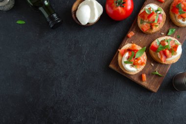 Doğranmış domates, fesleğen, mozzarella peyniri ve balsamik sirke ile İtalyan bruschetta. Taze ev yapımı caprese bruschetta veya crostini ve malzemelerin üzerine siyah arka plan, kopya alanı.