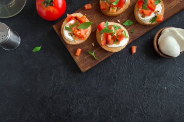 Doğranmış domates, fesleğen, mozzarella peyniri ve balsamik sirke ile İtalyan bruschetta. Taze ev yapımı caprese bruschetta veya crostini ve malzemelerin üzerine siyah arka plan, kopya alanı.