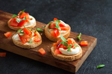 Doğranmış domates, fesleğen, mozzarella peyniri ve balsamik sirke ile İtalyan bruschetta. Taze ev yapımı caprese bruschetta veya crostini siyah taş zemin, kopya alanı üzerinde.