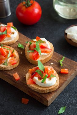 Doğranmış domates, fesleğen, mozzarella peyniri ve balsamik sirke ile İtalyan bruschetta. Taze ev yapımı caprese bruschetta veya crostini ve siyah arka plan üzerine malzemeler.