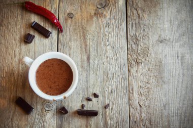 Biber ve rustik ahşap arka plan üzerinde çikolata parçaları ile sıcak çikolata. Ev yapımı sıcak çikolata içmek sonbahar ve kış tatilleri için.