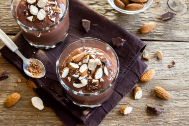 Sağlıklı çiğ Vegan çikolata badem ile tepesinde camlar ahşap arka plan üzerinde köpük yakın çekim - lezzetli ev yapımı çiğ Vegan çikolatalı puding ile fındık ve keçiboynuzu tozu