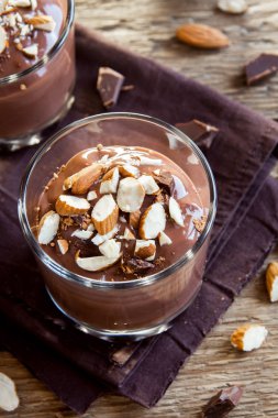 Sağlıklı çiğ Vegan çikolata badem ile tepesinde camlar ahşap arka plan üzerinde köpük yakın çekim - lezzetli ev yapımı çiğ Vegan çikolatalı puding ile fındık ve keçiboynuzu tozu