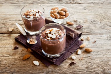 Sağlıklı çiğ Vegan çikolata badem ile tepesinde camlar ahşap arka plan üzerinde köpük yakın çekim - lezzetli ev yapımı çiğ Vegan çikolatalı puding ile fındık ve keçiboynuzu tozu