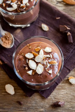 Sağlıklı çiğ Vegan çikolata badem ile tepesinde camlar ahşap arka plan üzerinde köpük yakın çekim - lezzetli ev yapımı çiğ Vegan çikolatalı puding ile fındık ve keçiboynuzu tozu