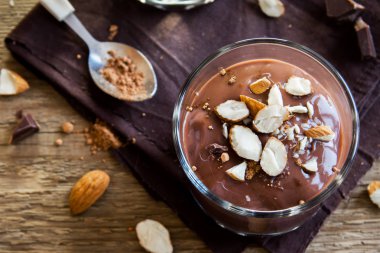 Çikolata Mousse ile badem ahşap arka plan üzerinde gözlük tepesinde yakın çekim - lezzetli ev yapımı çiğ Vegan çikolatalı puding ile fındık ve keçiboynuzu tozu