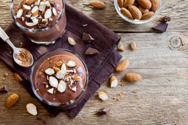 Sağlıklı çiğ Vegan çikolata badem ile tepesinde camlar ahşap arka plan üzerinde köpük yakın çekim - lezzetli ev yapımı çiğ Vegan çikolatalı puding ile fındık ve keçiboynuzu tozu
