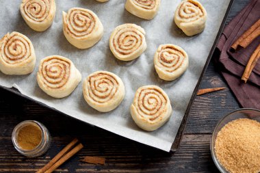 Rulo tarçın veya cinnabon, ev yapımı tarifi çiğ hamur hazırlık tatlı geleneksel tatlı çörekler pasta yemek. Gıda ingridients rulo tarçın için düz tepsi pişirme üzerinde yatıyordu.