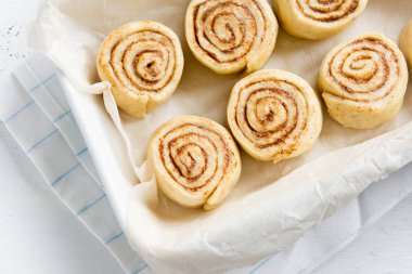 Rulo tarçın veya cinnabon, ev yapımı tarifi çiğ hamur hazırlık tatlı geleneksel tatlı çörekler pasta yemek. Ham tarçın rulo pişirme için hazır.