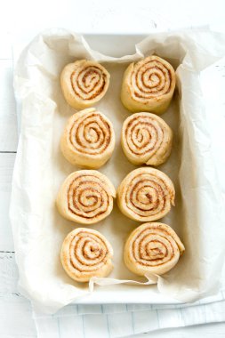 Rulo tarçın veya cinnabon, ev yapımı tarifi çiğ hamur hazırlık tatlı geleneksel tatlı çörekler pasta yemek pişirme tepsisi üzerinde.