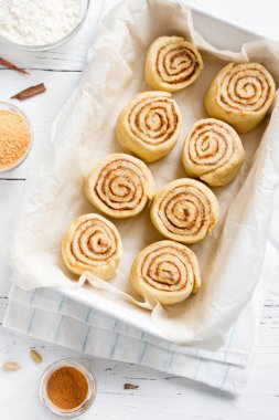 Rulo tarçın veya cinnabon, ev yapımı tarifi çiğ hamur hazırlık şekerli geleneksel tatlı çörek tepsisi pişirme üzerinde pasta malzemeler gıda ile.