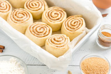 Rulo tarçın veya cinnabon, ev yapımı tarifi çiğ hamur hazırlık tatlı geleneksel tatlı çörekler pasta yemek. Beyaz masaya yiyecek ingridients için tarçın rulo.