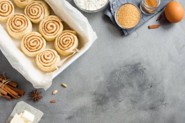 Rulo tarçın veya cinnabon, gri taş zemin, kopya alanı üzerine pasta malzemeler ile ev yapımı tarifi çiğ hamur hazırlık şekerli geleneksel tatlı buns.