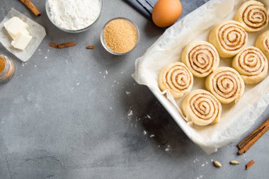 Rulo tarçın veya cinnabon, gri taş zemin, kopya alanı üzerine pasta malzemeler ile ev yapımı tarifi çiğ hamur hazırlık şekerli geleneksel tatlı buns.