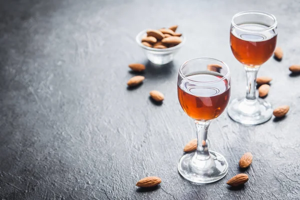 İtalyan likörü Amaretto badem siyah taş arka planda, kopya alanı ile