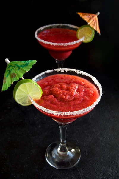 Strawberry Margarita cocktail with lime on black stone table, copy space. Frozen Margarita or Daiquiry Cocktail.