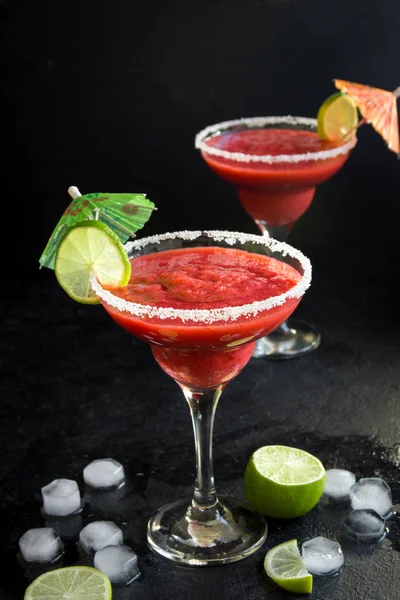 Strawberry Margarita cocktail with lime on black stone table, copy space. Frozen Margarita or Daiquiry Cocktail.