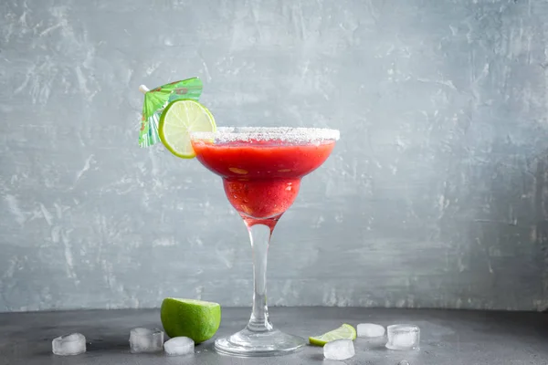 Strawberry Margarita cocktail with lime on grey stone table, copy space. Frozen Margarita or Daiquiry Cocktail.