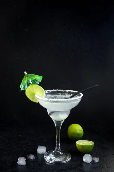 Margarita cocktail with lime and ice on black stone background, copy space. Classic Margarita or Daiquiry Cocktail.