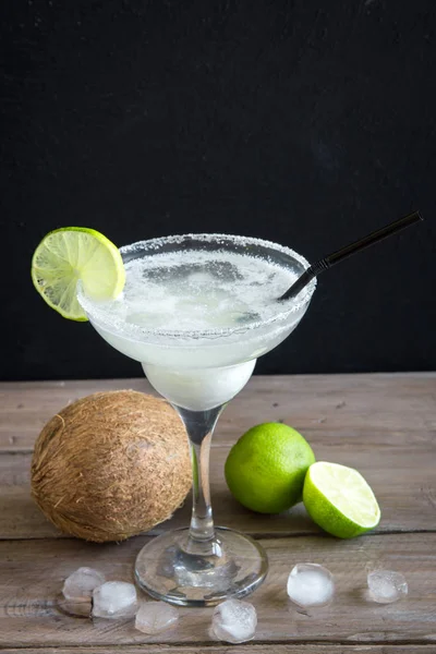 Coconut Margarita cocktail with lime on dark wooden table, copy space. White Margarita or Daiquiry Cocktail.
