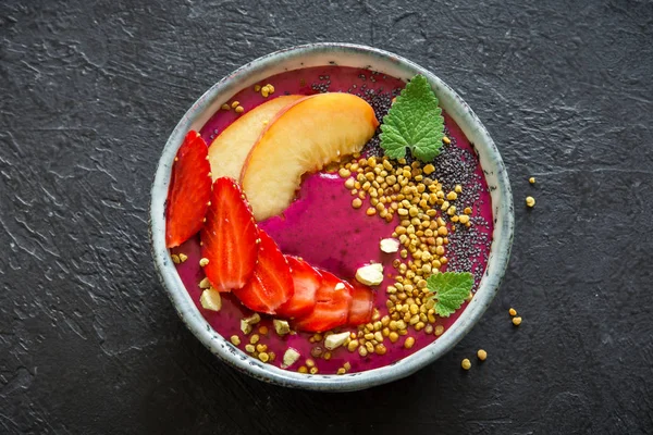Acai smoothie kaseyle chia tohum, meyve, meyve (çilek) ve arı polen sağlıklı vegan vejetaryen diyet çiğ kahvaltı için. Siyah arka plan üzerine güler yüzlü kase kahvaltı.