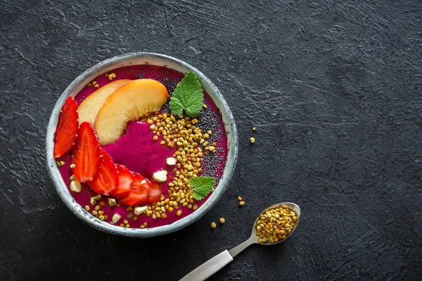 Acai smoothie kaseyle chia tohum, meyve, meyve (çilek) ve arı polen sağlıklı vegan vejetaryen diyet çiğ kahvaltı için. Siyah arka plan üzerine güler yüzlü kase kahvaltı.