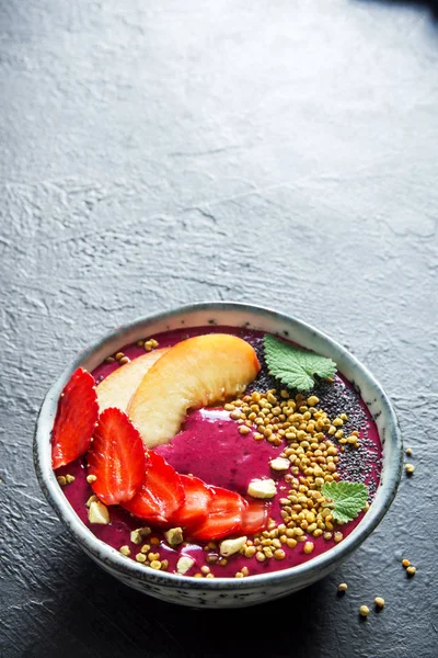 Acai smoothie kaseyle chia tohum, meyve, meyve (çilek) ve arı polen sağlıklı vegan vejetaryen diyet çiğ kahvaltı için. Güler yüzlü kase siyah arka plan üzerine kahvaltı, alanı Kopyala.