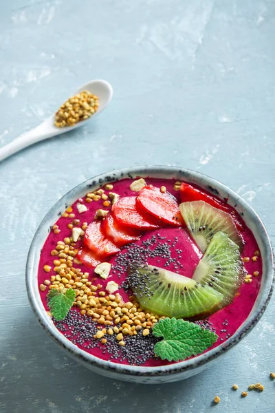 Acai smoothie kaseyle chia tohum, meyve, meyve (çilek) ve arı polen sağlıklı vegan vejetaryen diyet çiğ kahvaltı için. Kahvaltı Smoothie kase mavi zemin üzerine.