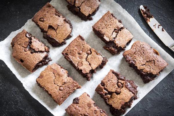 Çift çikolatalı kek. Ev yapımı çikolata fudge kek pişirme kağıdı ve siyah arka plan üzerinde çikolata parçaları ile.