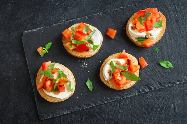 Doğranmış domates, fesleğen, mozzarella peyniri ve balsamik sirke ile İtalyan bruschetta. Taze ev yapımı caprese bruschetta veya crostini siyah taş zemin, kopya alanı üzerinde.