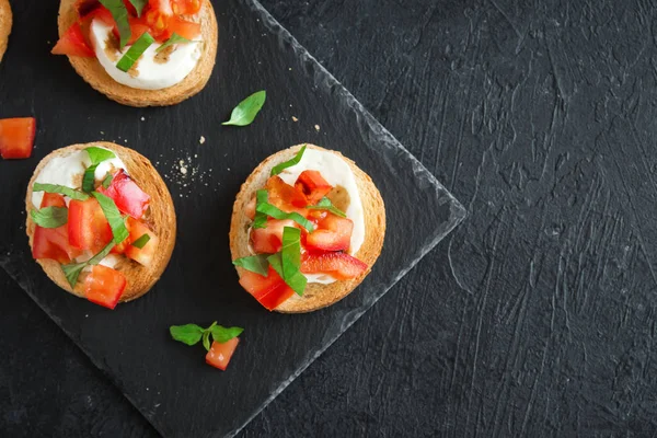 Doğranmış domates, fesleğen, mozzarella peyniri ve balsamik sirke ile İtalyan bruschetta. Taze ev yapımı caprese bruschetta veya crostini siyah taş zemin, kopya alanı üzerinde.