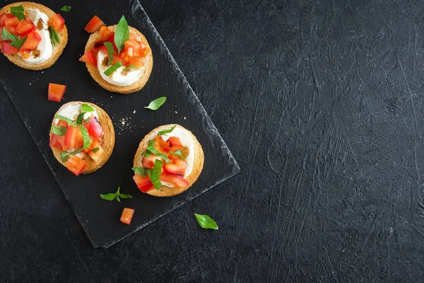Doğranmış domates, fesleğen, mozzarella peyniri ve balsamik sirke ile İtalyan bruschetta. Taze ev yapımı caprese bruschetta veya crostini siyah taş zemin, kopya alanı üzerinde.