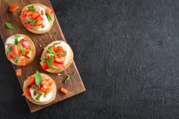 Doğranmış domates, fesleğen, mozzarella peyniri ve balsamik sirke ile İtalyan bruschetta. Taze ev yapımı caprese bruschetta veya crostini siyah taş zemin, kopya alanı üzerinde.