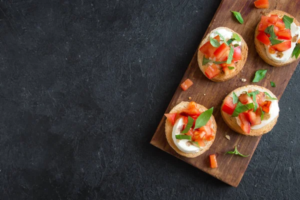 Doğranmış domates, fesleğen, mozzarella peyniri ve balsamik sirke ile İtalyan bruschetta. Taze ev yapımı caprese bruschetta veya crostini siyah taş zemin, kopya alanı üzerinde.
