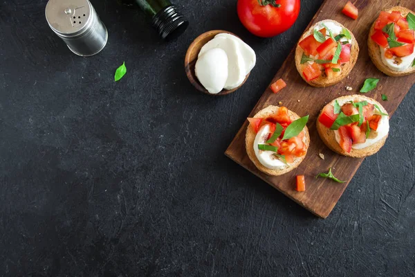 Doğranmış domates, fesleğen, mozzarella peyniri ve balsamik sirke ile İtalyan bruschetta. Taze ev yapımı caprese bruschetta veya crostini siyah taş zemin, kopya alanı üzerinde.