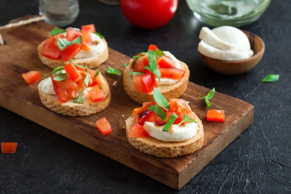 Doğranmış domates, fesleğen, mozzarella peyniri ve balsamik sirke ile İtalyan bruschetta. Taze ev yapımı caprese bruschetta veya crostini ve malzemelerin üzerine siyah arka plan, kopya alanı.