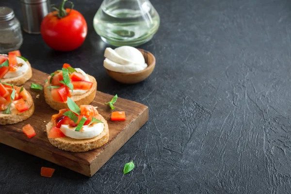 Doğranmış domates, fesleğen, mozzarella peyniri ve balsamik sirke ile İtalyan bruschetta. Taze ev yapımı caprese bruschetta veya crostini ve malzemelerin üzerine siyah arka plan, kopya alanı.