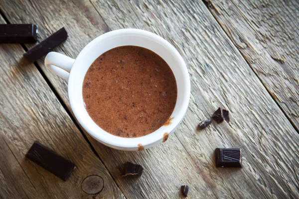 Sıcak çikolata ve çikolata parçaları rustik ahşap arka plan üzerinde. Ev yapımı sıcak çikolata içmek sonbahar ve kış tatilleri için.